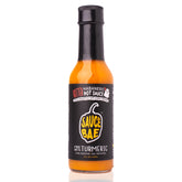 Front view of Sauce Bae Hotter Habanero Hot Sauce bottle featuring a black label with a yellow pepper logo, ghost pepper icon, and bold text highlighting turmeric, pineapple, and ghost pepper ingredients. 5 fl oz glass bottle with vibrant orange sauce inside, photographed on a white background.